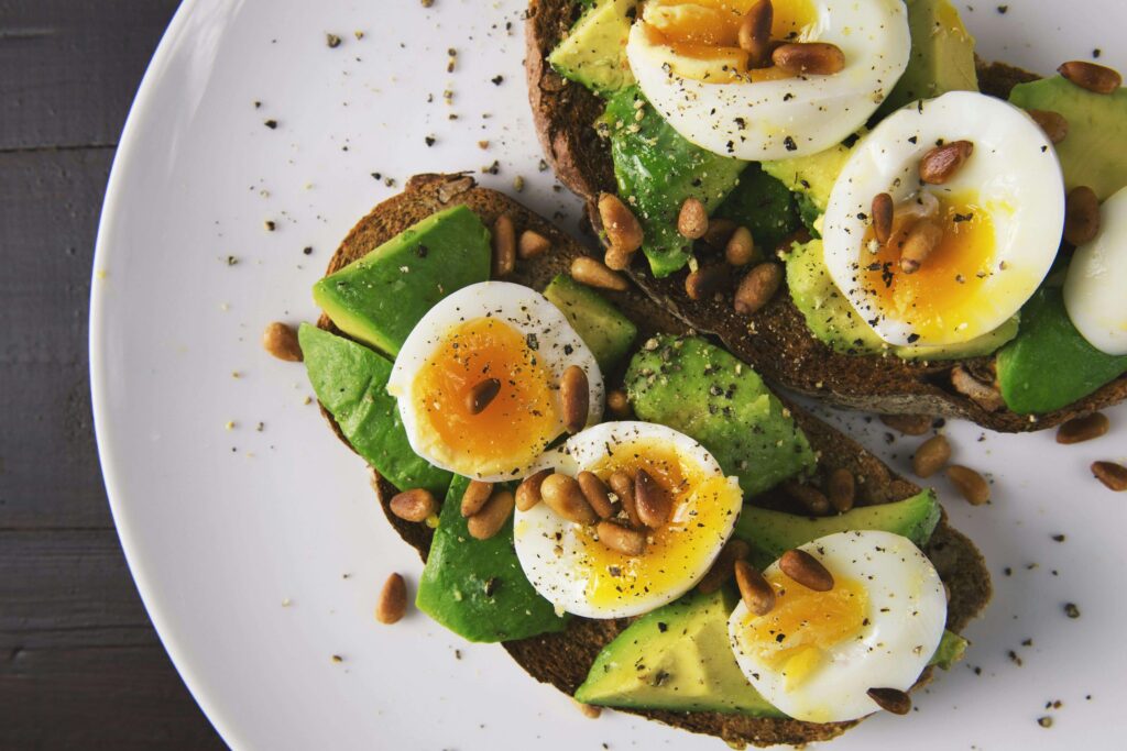 avocado toast topped with eggs and pine nuts