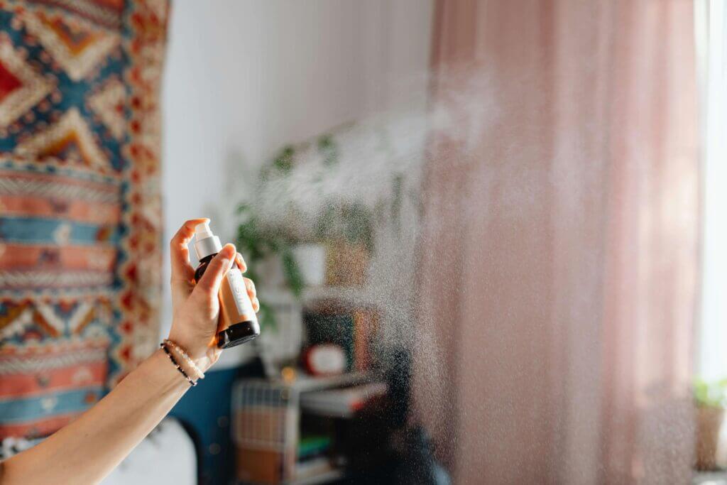 spraying natural air freshener at home