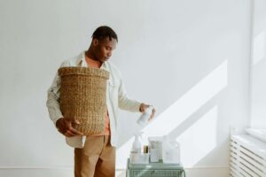 a man holding a laundry basket in one hand and laundry detergent in the other