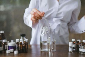 a person in a lab coat surrounded by unlabeled vials